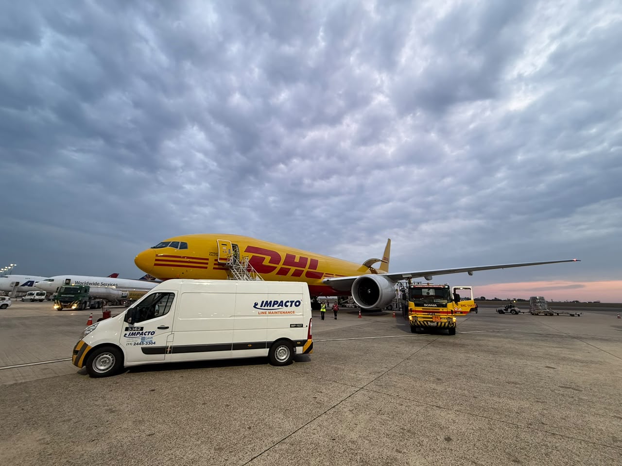 Impacto Aviation line maintenance vehicle next to a DHL aircraft