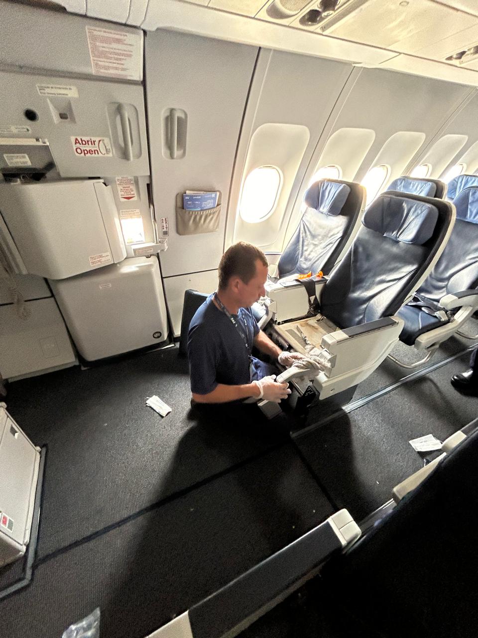 Technician sanitizing a seat armrest and tray table