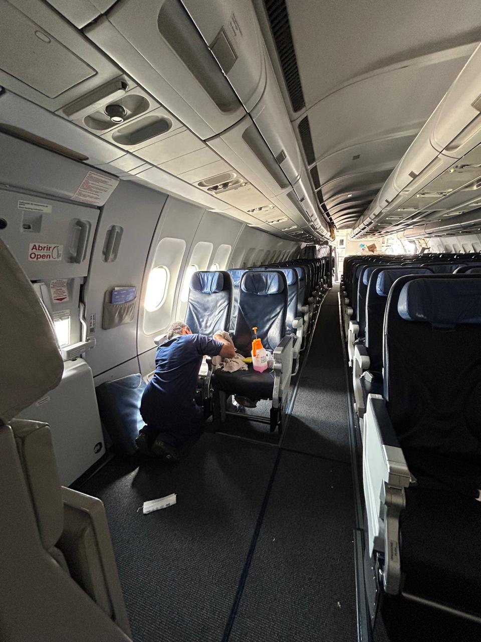 Technician sanitizing seats in the cabin aisle